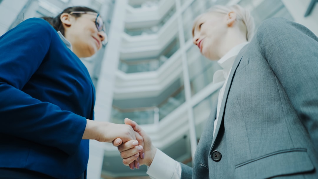 Two colleagues shaking hands in an office, representing an agency partnership